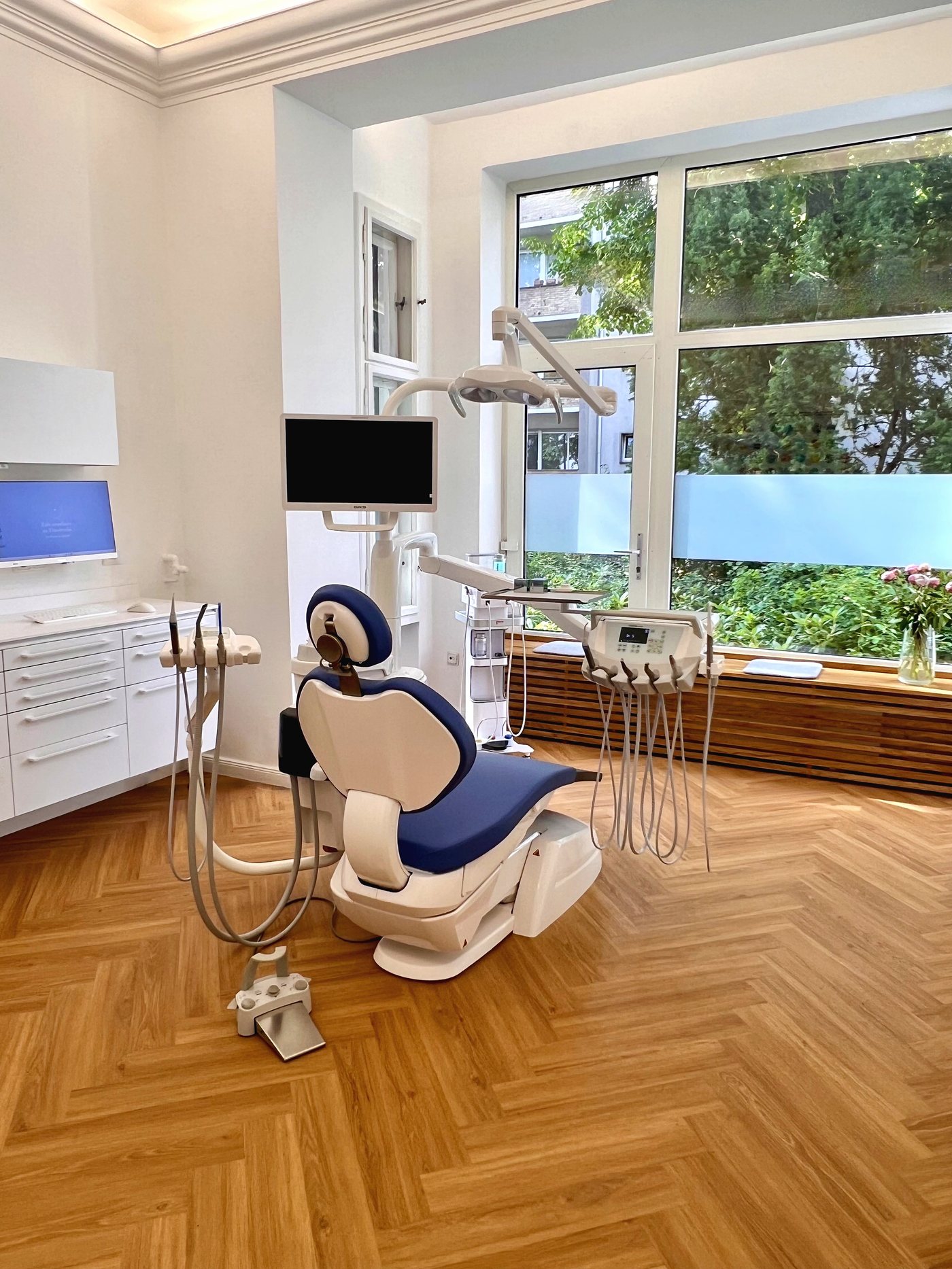 Behandlungszimmer mit modernem Behandlungsstuhl und Blick ins Grüne